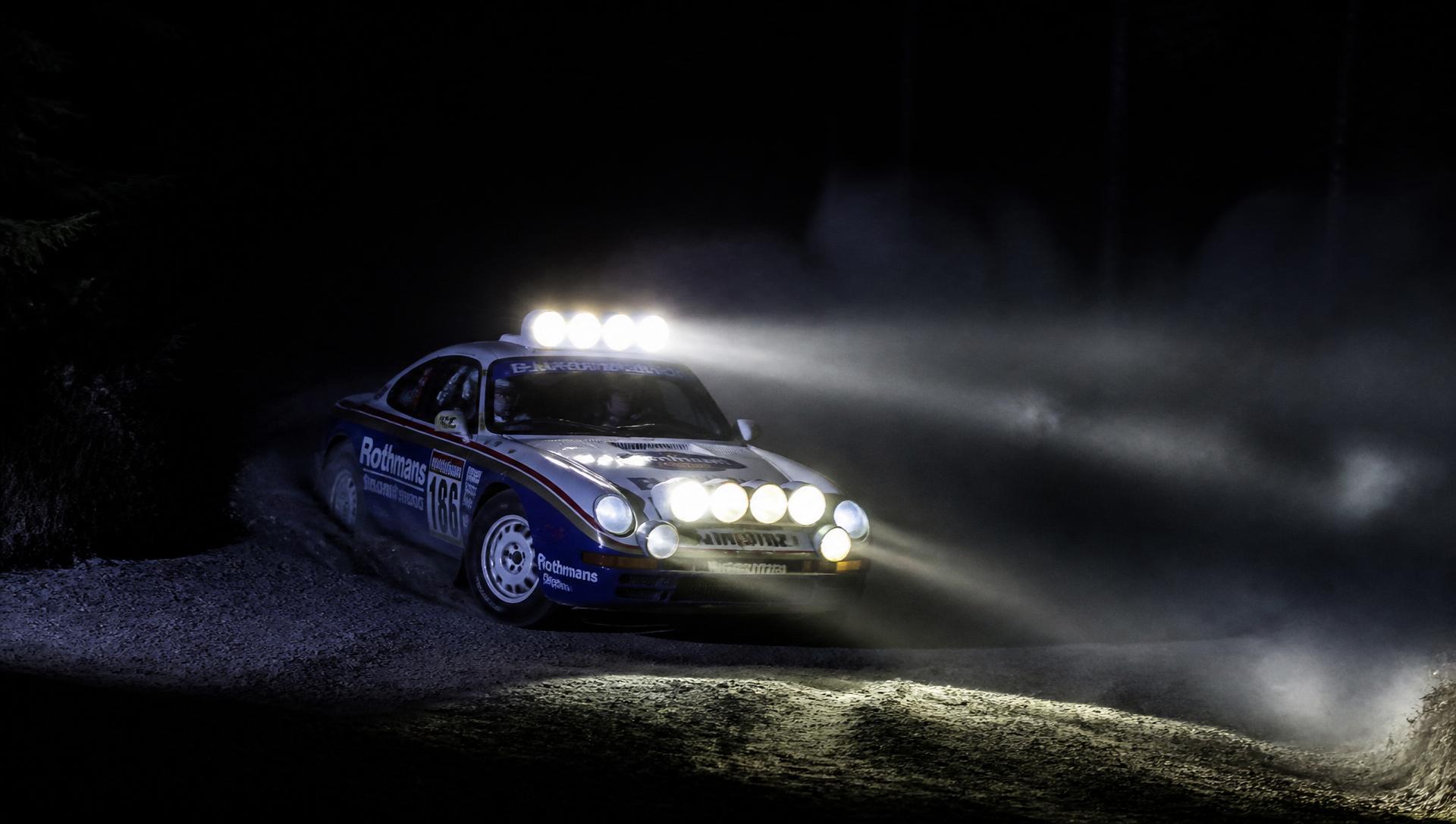 Rally car cutting through a night stage with auxiliary lights blazing